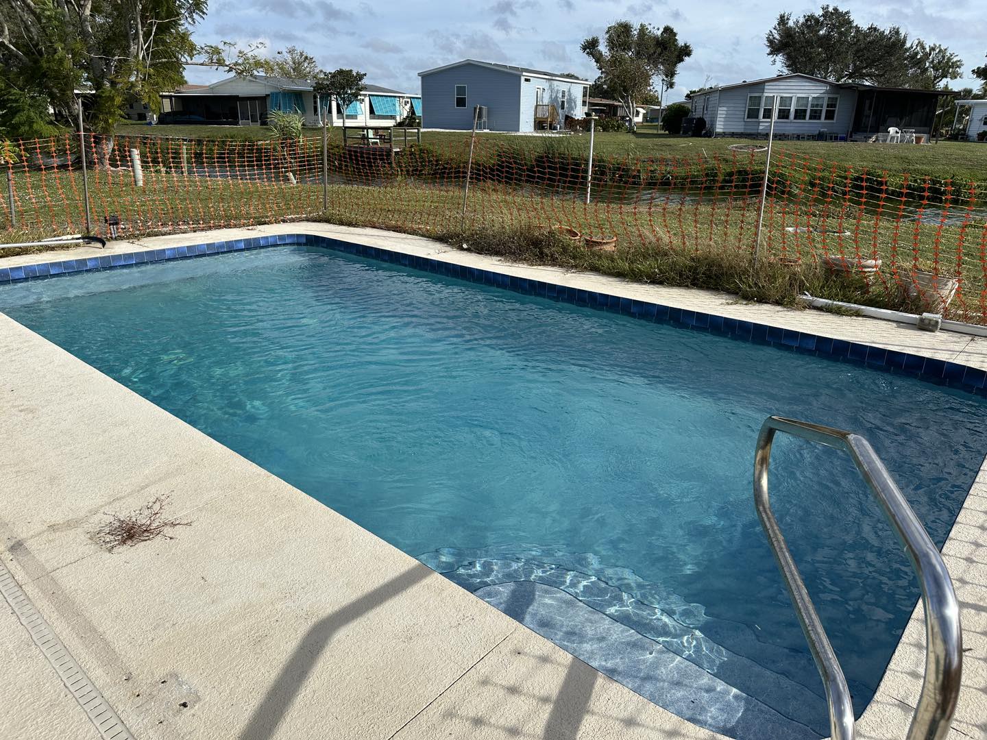 A pool with a fence and some houses in the background